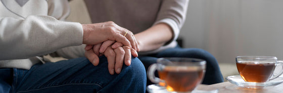 I family member supporting a loved one with diabetes while sitting together  on a couch with 2 cups of tea on a table next to them